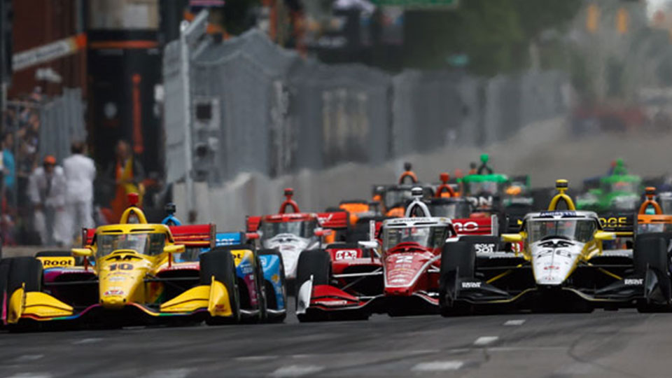 The field of INDYCARS race against each other.