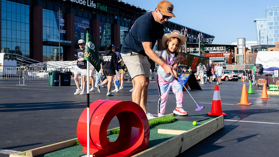 A father and daughter play a game in the Fan Zone